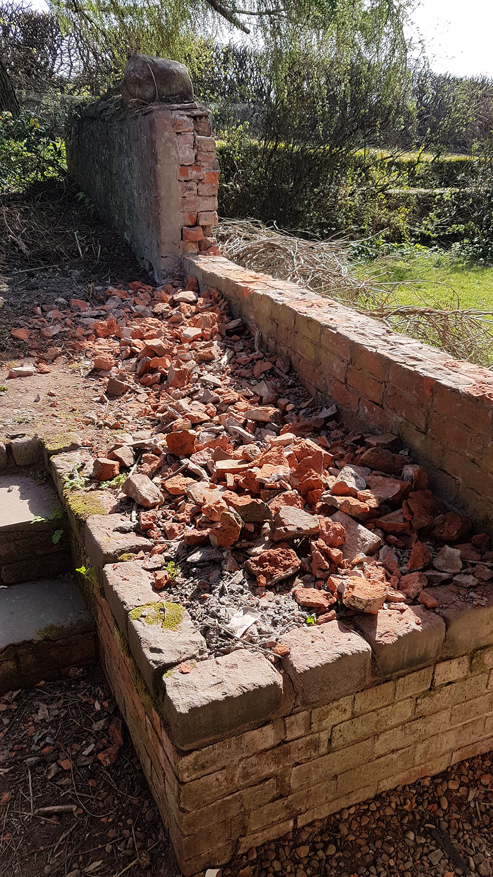 A brick wall, partly demolished.